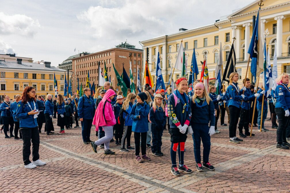 Partiolaisia partioasussa ja lippujen kanssa Senaatintorilla.