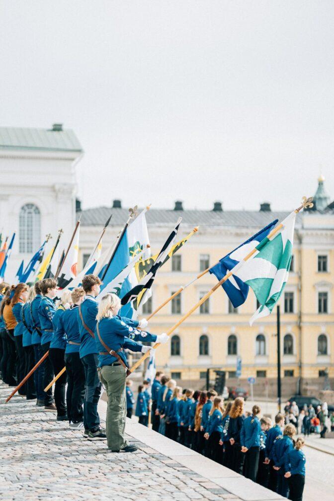 Lippukuntien lippuja kantajineen Tuomikirkon portailla.